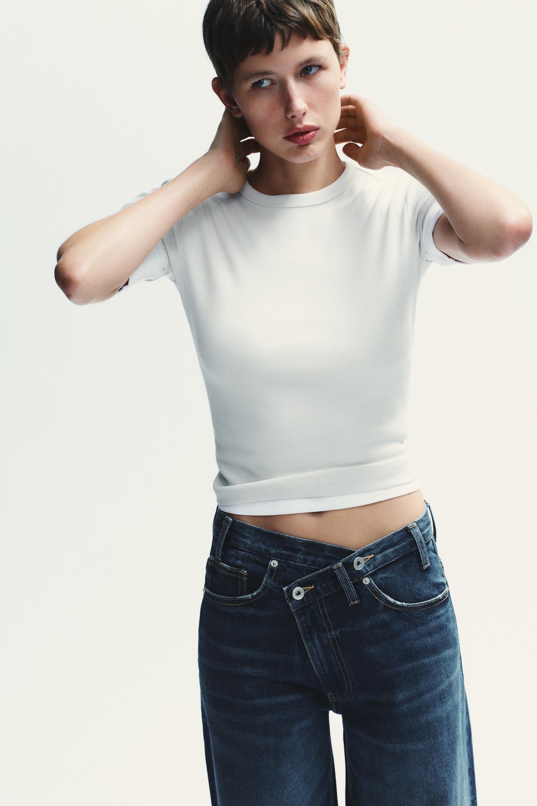 Weit geschnittene High-Waist-Jeans mit überkreuzten Beinen