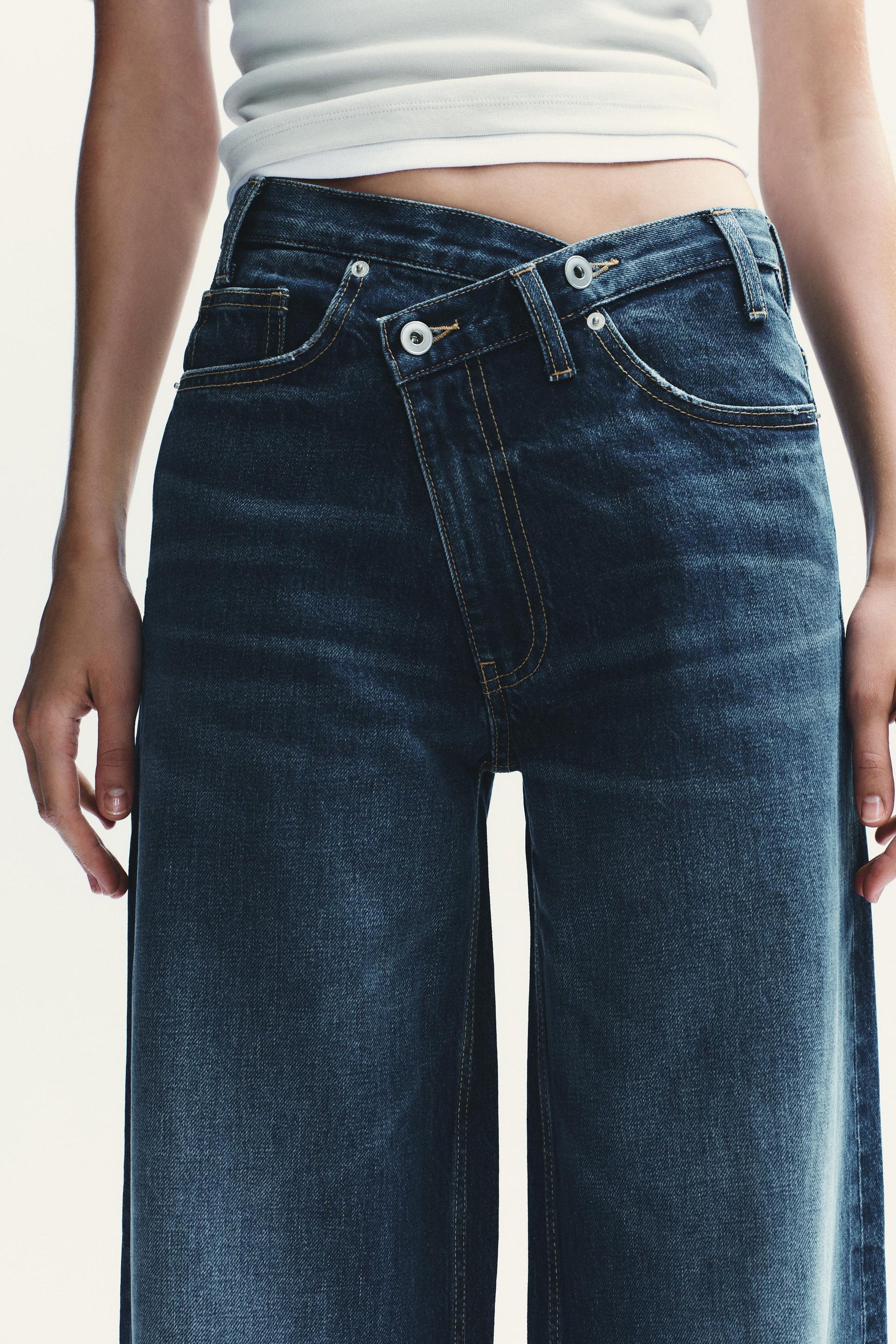 Weit geschnittene High-Waist-Jeans mit überkreuzten Beinen