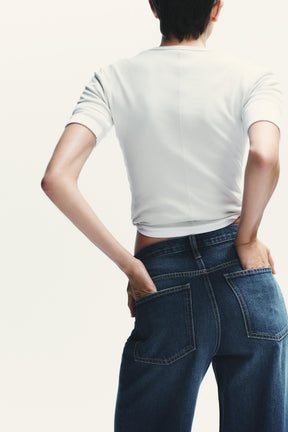 Weit geschnittene High-Waist-Jeans mit überkreuzten Beinen